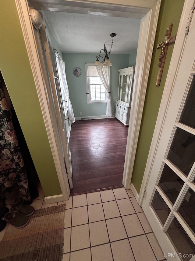 doorway to outside featuring visible vents, baseboards, and light tile patterned flooring