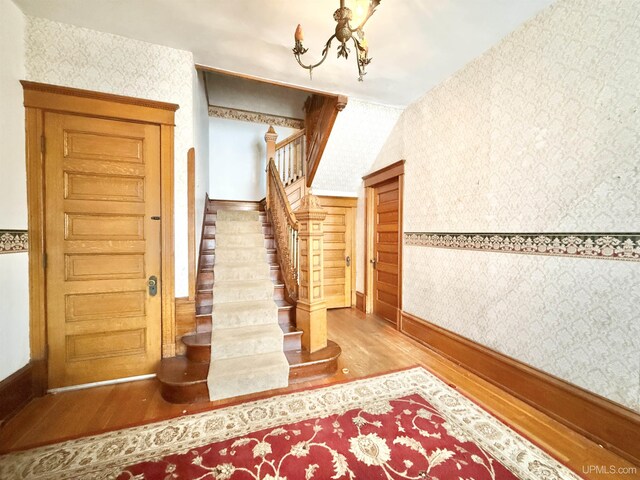 404 Lake Shore Dr, Escanaba, MI 49829 - stairway with wallpapered walls, wood finished floors, a chandelier, and baseboards