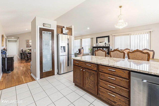 kitchen featuring light stone counters, a chandelier, decorative light fixtures, lofted ceiling, and appliances with stainless steel finishes