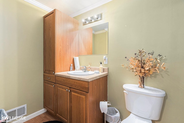 bathroom featuring visible vents, toilet, crown molding, vanity, and wood finished floors