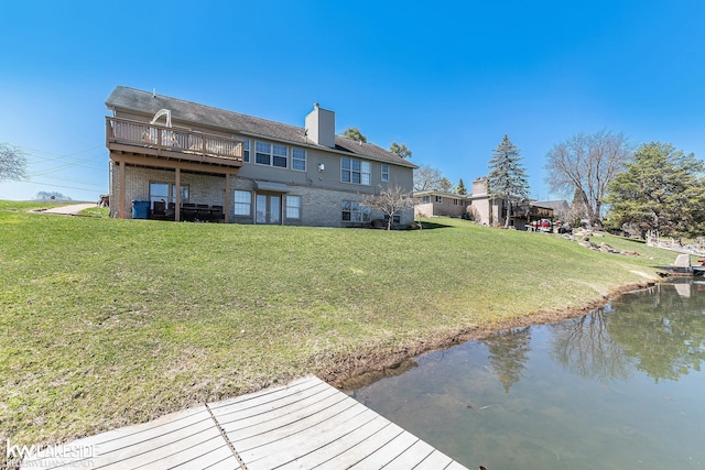 back of house with a water view, a lawn, and a chimney