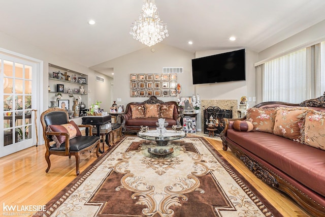 living room featuring wood finished floors, vaulted ceiling, visible vents, and a wealth of natural light