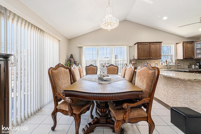 dining area with light tile patterned floors, ceiling fan with notable chandelier, and lofted ceiling