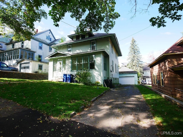 view of front of home with a detached garage, an outbuilding, and a front lawn