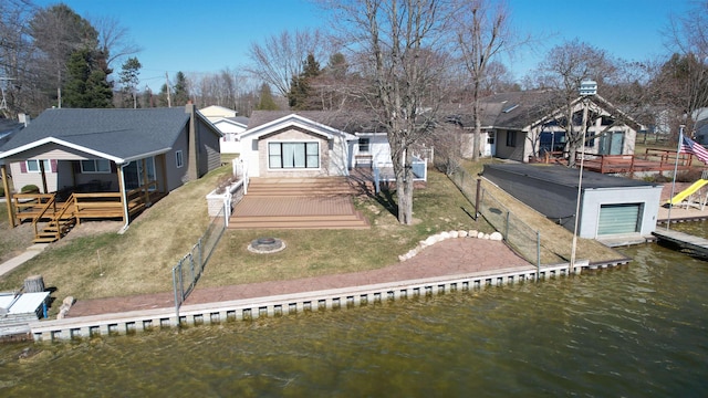 rear view of house with a deck with water view and a lawn