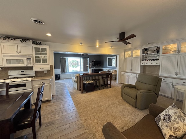 living area with light wood-style flooring, ceiling fan, and visible vents