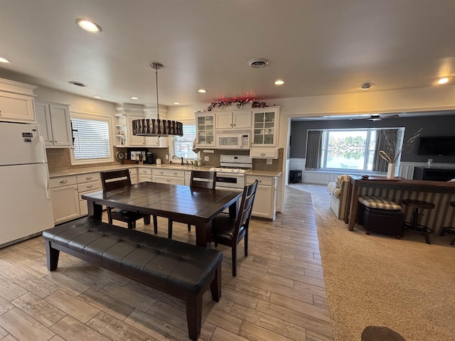 dining room featuring recessed lighting, plenty of natural light, visible vents, and light wood-style flooring