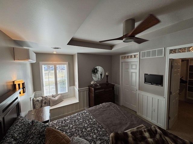 carpeted bedroom with a decorative wall, visible vents, a wainscoted wall, and a wall unit AC