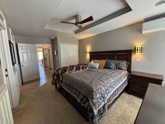 bedroom with a closet, a ceiling fan, visible vents, a wall unit AC, and a raised ceiling