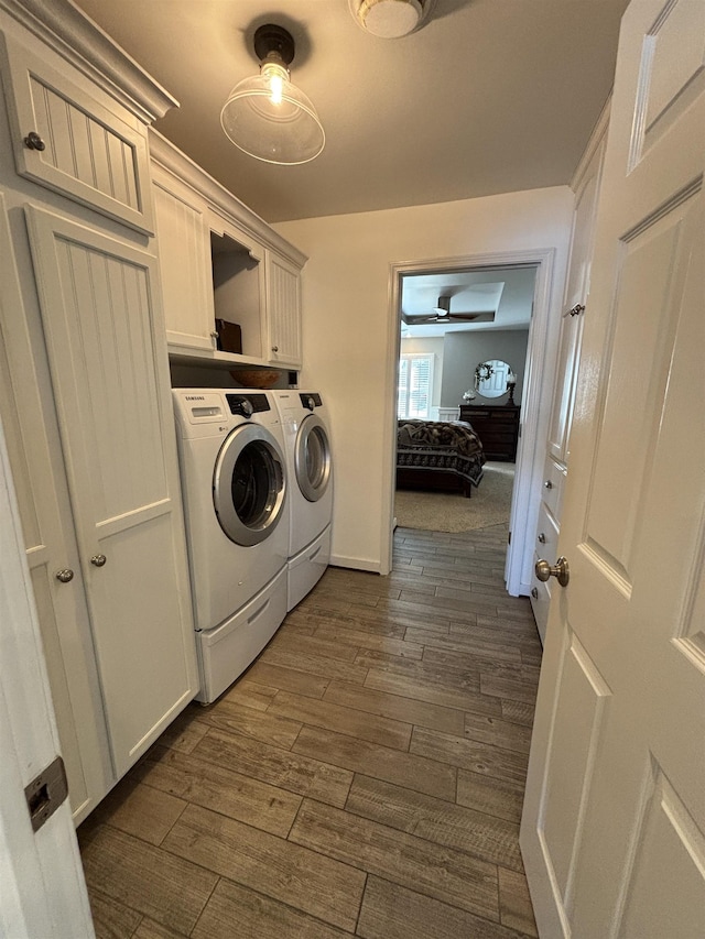 clothes washing area with cabinet space, washing machine and clothes dryer, ceiling fan, and dark wood-style floors