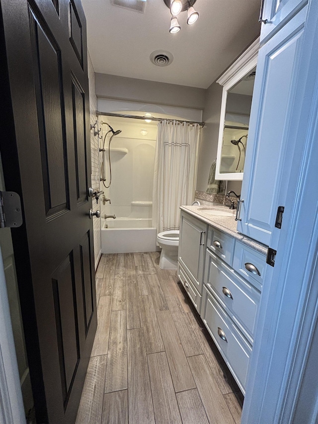 full bathroom featuring vanity, toilet, visible vents, shower / bath combo with shower curtain, and wood finished floors