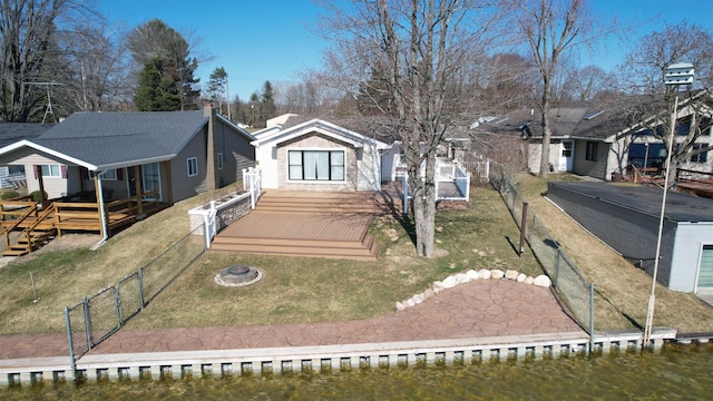 view of front of home featuring a front yard, a deck with water view, a residential view, and fence private yard