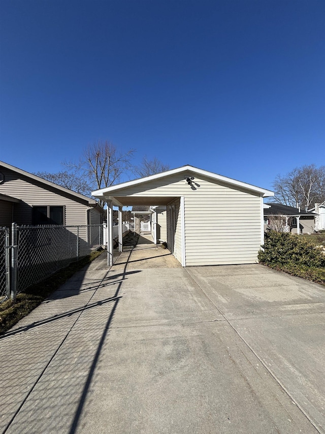 exterior space with an outbuilding, fence, an attached carport, and concrete driveway