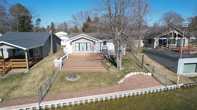 view of front of property featuring a fenced backyard, a deck with water view, a front lawn, and a dock