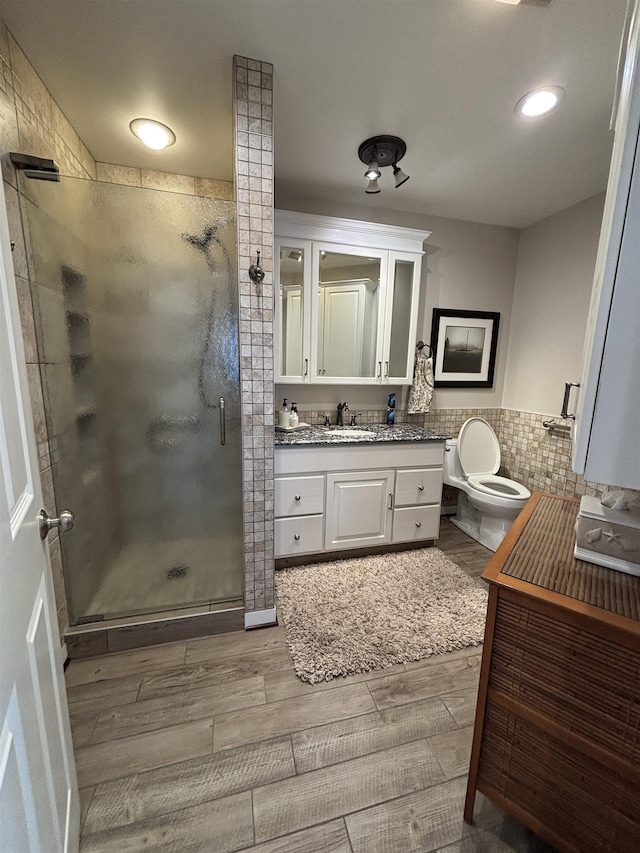 full bathroom featuring toilet, vanity, a stall shower, and wood finished floors