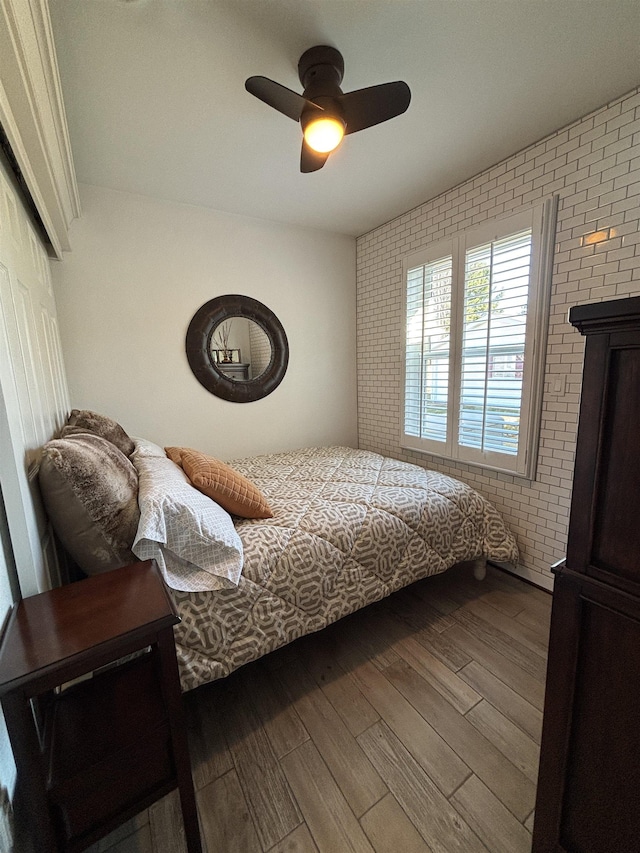 bedroom featuring brick wall, a closet, a ceiling fan, and wood finished floors