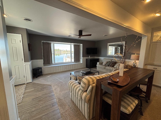 living room featuring a wealth of natural light, visible vents, a ceiling fan, and a wainscoted wall