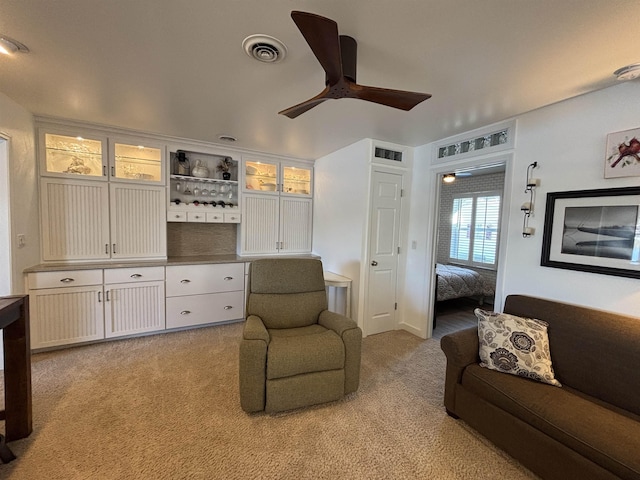 living area featuring visible vents, light colored carpet, and ceiling fan