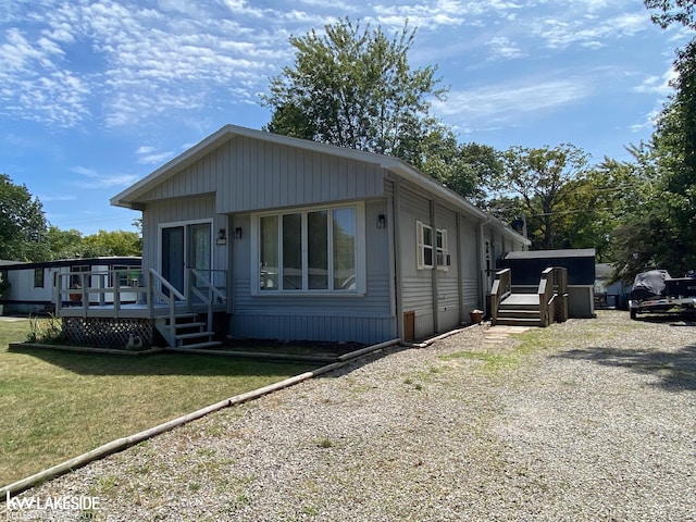 view of front of property featuring a front lawn, a wooden deck, and driveway