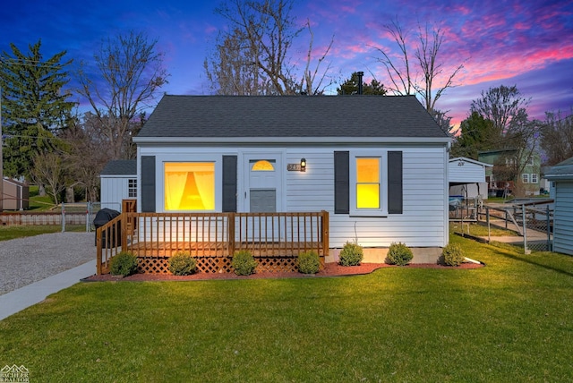 bungalow with a shingled roof, a front yard, and fence