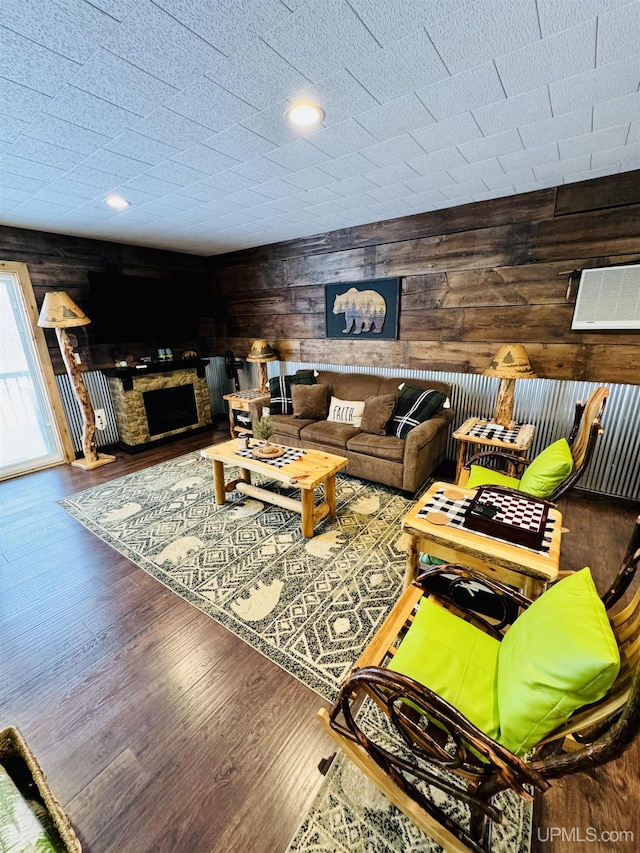 living room with wood walls, a fireplace, and wood finished floors