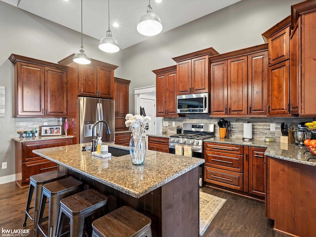 kitchen featuring light stone countertops, a towering ceiling, appliances with stainless steel finishes, a sink, and backsplash