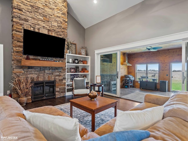living room with ceiling fan, wood finished floors, high vaulted ceiling, and a fireplace
