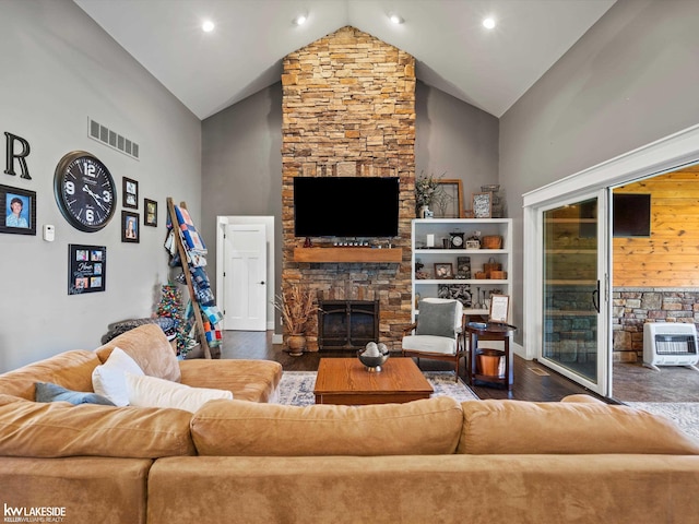 living room featuring visible vents, heating unit, a fireplace, wood finished floors, and high vaulted ceiling