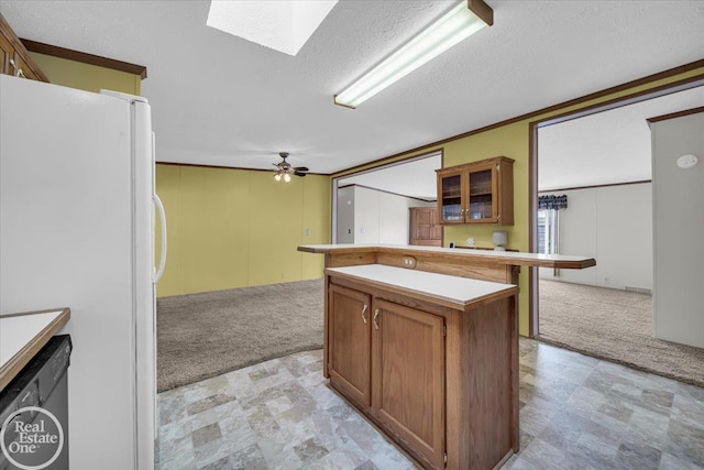 6240 Twin Lakes Dr, Kimball, MI 48074 - kitchen with light countertops, freestanding refrigerator, brown cabinetry, a skylight, and light colored carpet