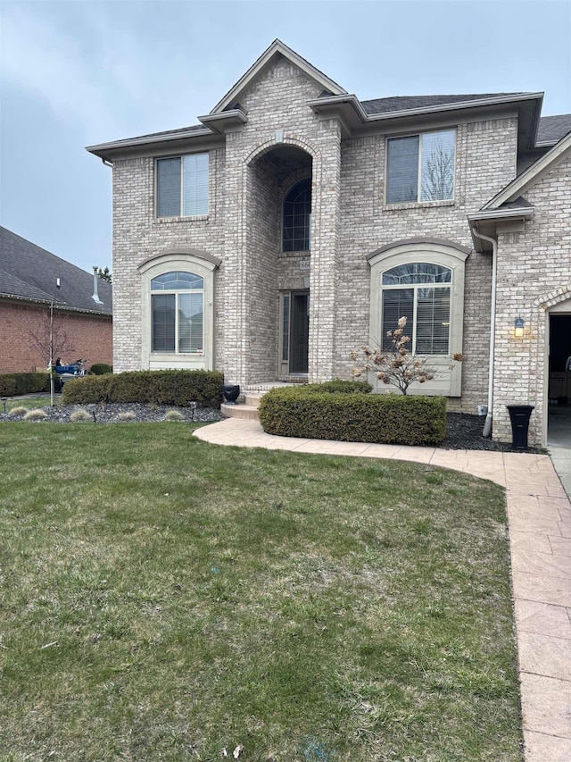 french provincial home with brick siding and a front lawn