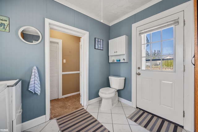 bathroom with baseboards, tile patterned floors, crown molding, toilet, and washer and dryer