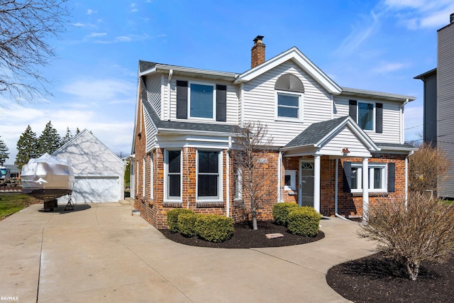 traditional home with a chimney, an outbuilding, a detached garage, and brick siding
