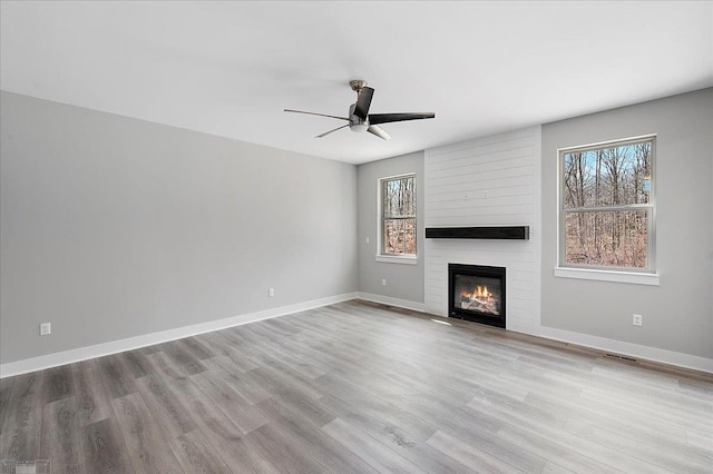 unfurnished living room featuring a ceiling fan, plenty of natural light, and wood finished floors