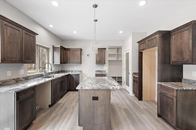 kitchen featuring a sink, dark brown cabinets, light wood finished floors, and a kitchen island
