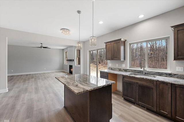 kitchen with a sink, a wealth of natural light, a ceiling fan, and light stone countertops