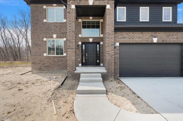 entrance to property with a garage, concrete driveway, and brick siding