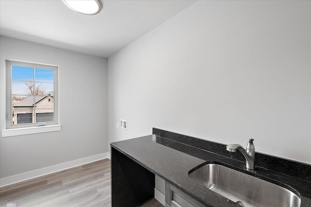 home office with a sink, baseboards, and light wood-type flooring
