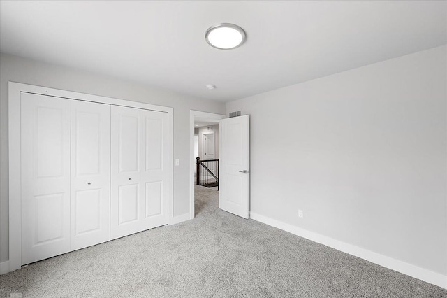unfurnished bedroom featuring carpet floors, baseboards, and a closet