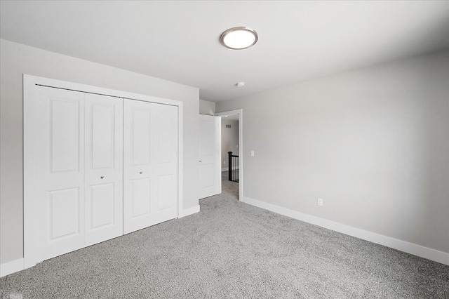 unfurnished bedroom with a closet, carpet, and baseboards