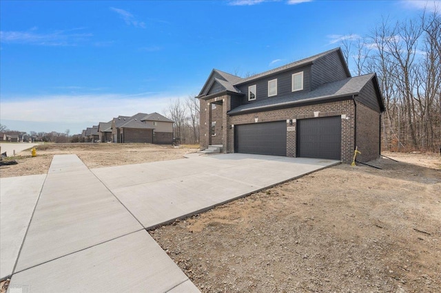 view of side of property with a garage, brick siding, and driveway
