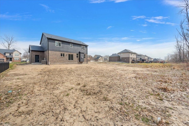 back of property featuring central air condition unit, fence, a residential view, and brick siding