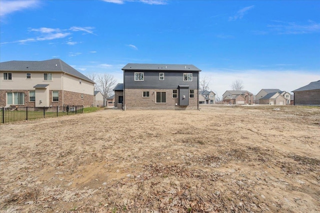 back of house featuring a residential view, brick siding, and fence