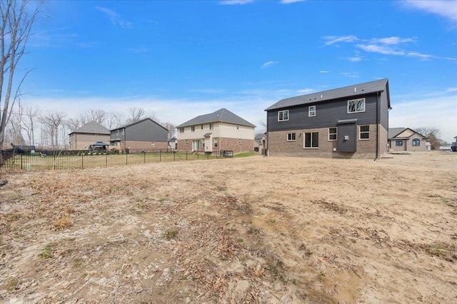 rear view of house featuring brick siding and fence