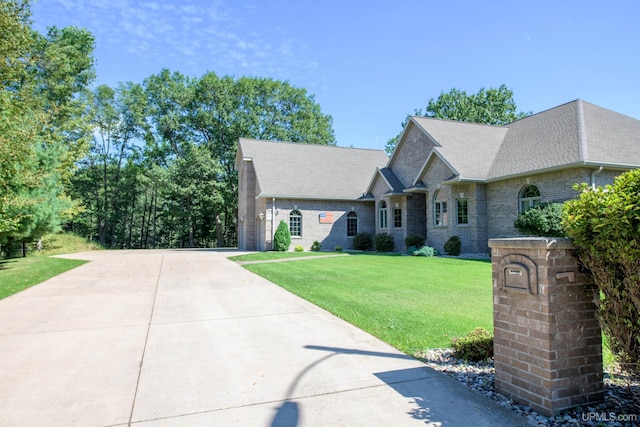 view of front of home featuring a front yard, a shingled roof, and brick siding