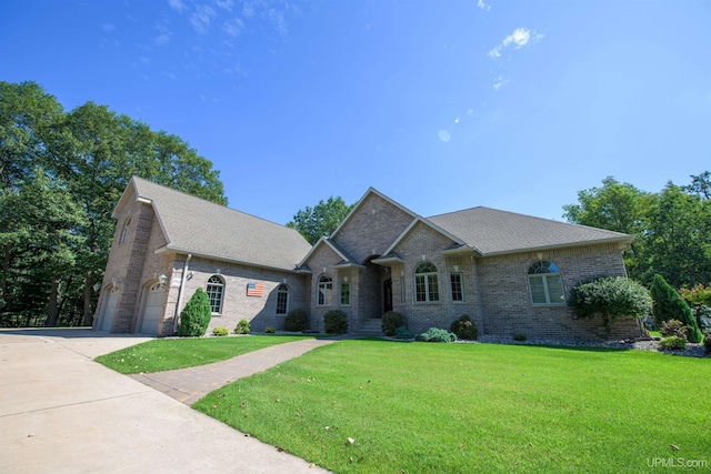ranch-style home with brick siding, roof with shingles, a front lawn, and concrete driveway