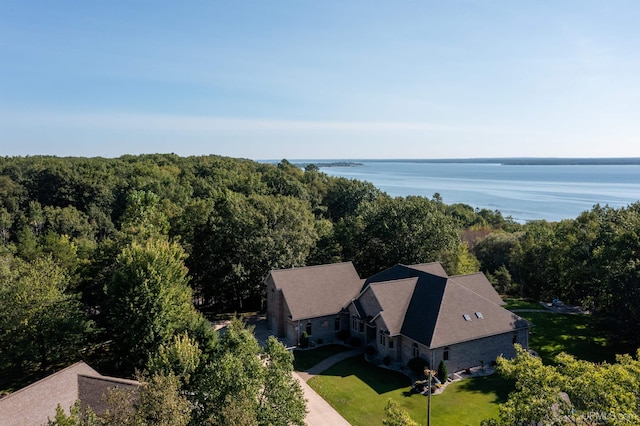 drone / aerial view with a wooded view and a water view