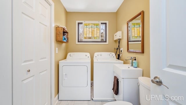 clothes washing area featuring laundry area, washing machine and clothes dryer, and light tile patterned floors