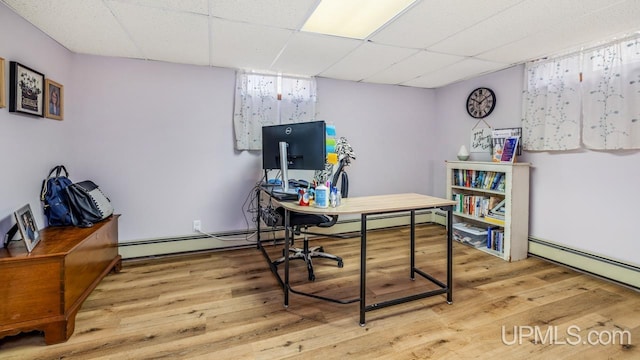 office area featuring a baseboard radiator, light wood-style floors, and a drop ceiling