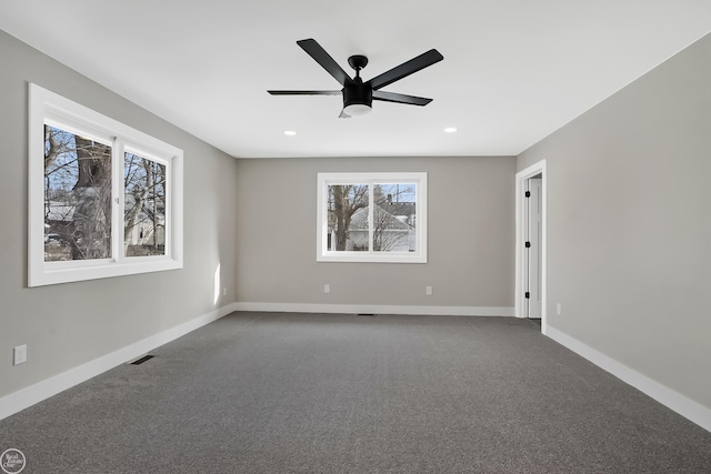 spare room with recessed lighting, dark colored carpet, visible vents, a ceiling fan, and baseboards