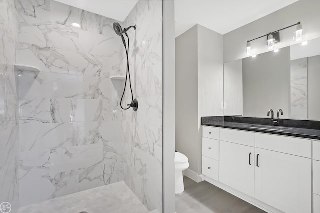 bathroom with wood finished floors, toilet, vanity, and a marble finish shower